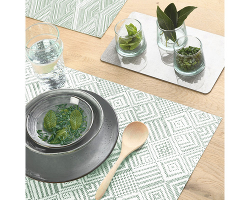 Décoration de table avec assiettes, verres, herbes aromatiques, cuillère en bois et sets de table à motifs