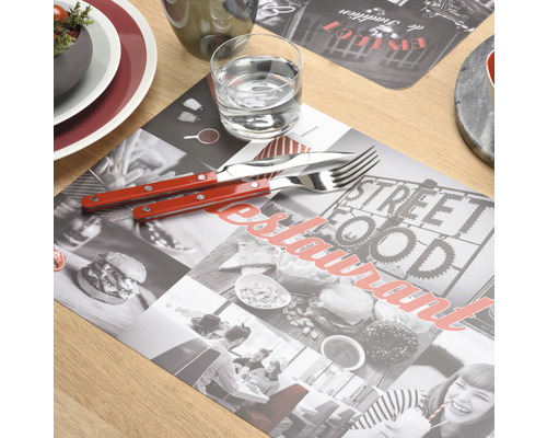 Tischdekoration mit Platzdeckchen, Besteck und Glas auf einem Holztisch