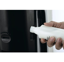 Une main introduit un flacon dans un distributeur.