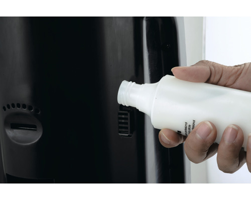 Une main introduit un flacon dans un distributeur.