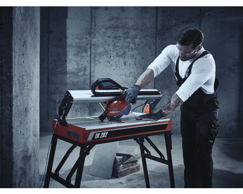 Ein Mann benutzt eine Fliesenschneidmaschine TR 202 zum Zuschneiden von Fliesen.