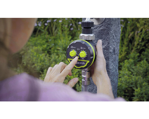 Eine Person stellt einen Bewässerungscomputer der Marke SEKA an einem Wasserhahn ein.