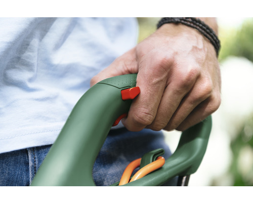 Hand hält einen Rasentrimmer mit Sicherheitsschalter