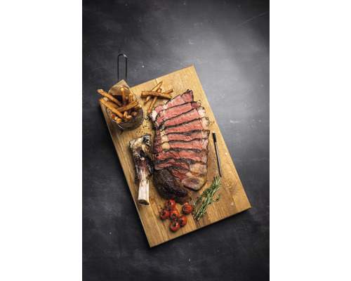 Steak Tomahawk avec frites, tomates et romarin sur une planche en bois