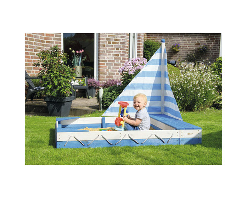 Bac à sable en forme de bateau avec enfant dans le jardin