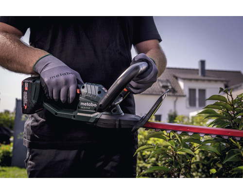 Person bedient eine Metabo Akku-Heckenschere zum Beschneiden einer Hecke