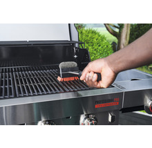 Personne nettoyant une grille de barbecue avec une brosse pour barbecue
