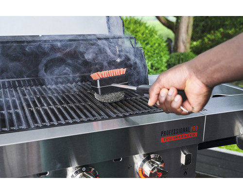 Une personne nettoie un barbecue avec une brosse de barbecue.