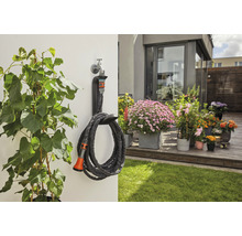 Scène de jardin avec plantes, terrasse et tuyau d''arrosage enroulé avec support mural