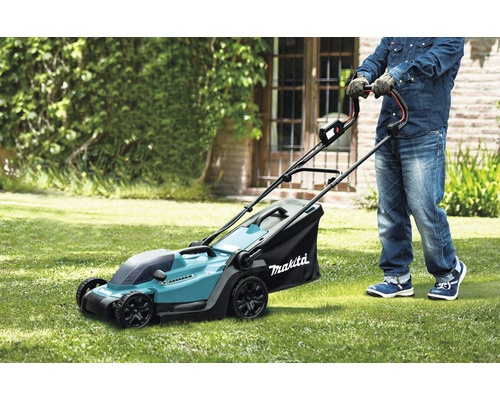 Eine Person benutzt einen Rasenmäher der Marke Makita auf einer Rasenfläche.