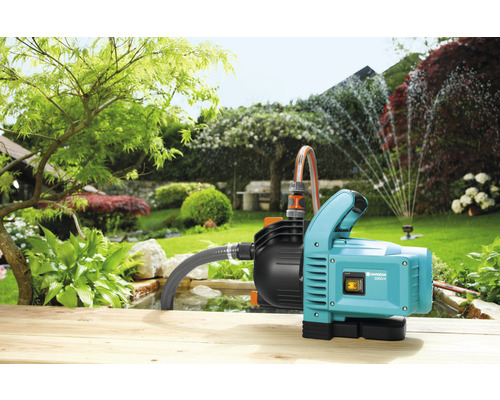 Gartenszene mit Bewässerungspumpe und Rasensprenger im Einsatz