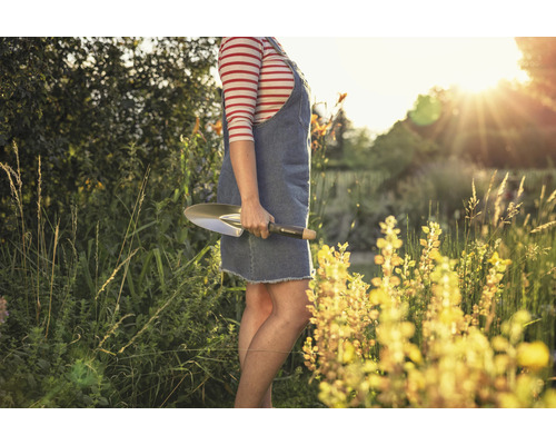 Femme tenant une plantoir dans le jardin.