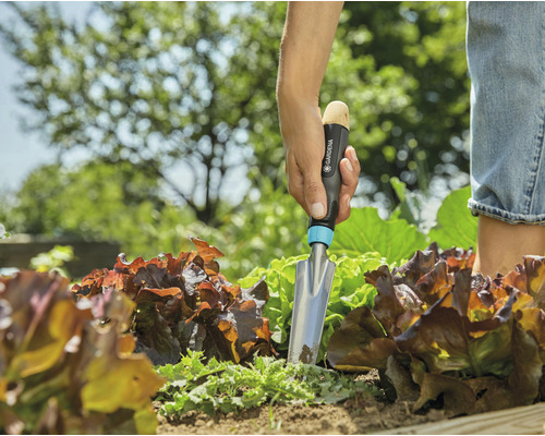 Eine Person verwendet eine Gardena Pflanzschaufel in einem Gartenbeet.