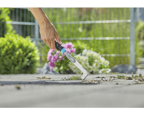 Gros plan d''une personne en train d''enlever des mauvaises herbes avec un désherbeur de joints