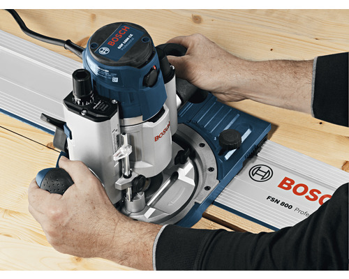 Person benutzt Oberfräse auf einer Führungsschiene von Bosch