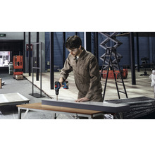 Un homme perce un trou dans une pièce à l''aide d''une perceuse sans fil dans un atelier.