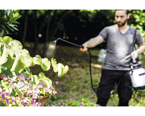 Mann verwendet Gartenspritze zur Pflanzenbehandlung