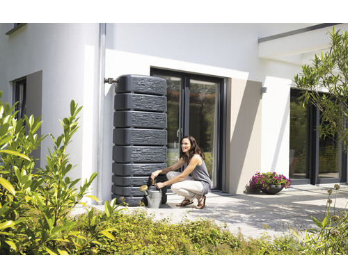 Regenspeicher mit Wasserhahn und Frau, die eine Giesskanne befüllt