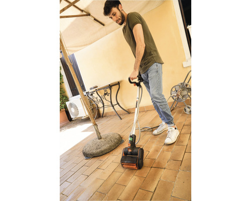 Un homme utilise un nettoyeur de terrasse électrique sur une terrasse carrelée.