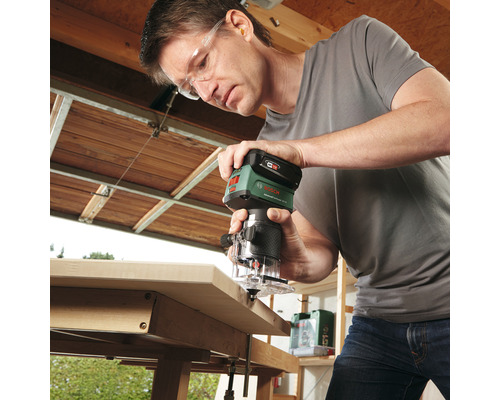 Mann arbeitet mit einer Oberfräse an einem Werkstück.