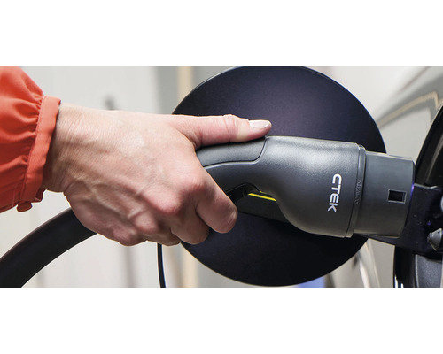 Une main tient un chargeur CTEK pour voitures électriques.