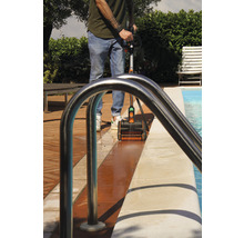 Une personne nettoie la zone de la piscine avec une brosse.