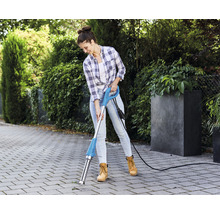 Une femme utilise une machine électrique à gratter les joints sur un chemin pavé pour jardiner.
