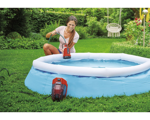 Une femme utilise une pompe de piscine Einhell pour vider une piscine dans le jardin.