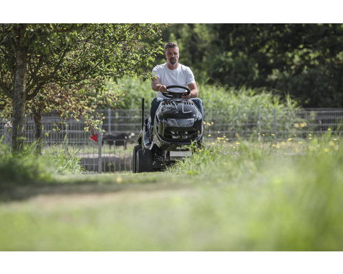 Un homme conduit un tracteur de pelouse dans un champ