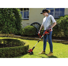 Femme utilisant un coupe-bordures à batterie dans le jardin.