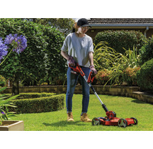 Une femme utilise un coupe-bordures à batterie dans le jardin.