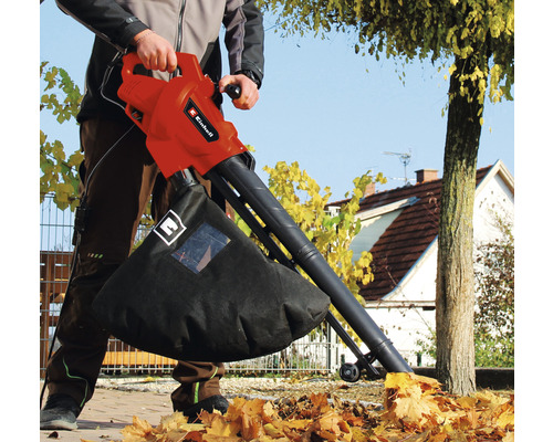 Eine Person benutzt einen Laubsauger von Einhell zum Aufsaugen von Laub im Garten.