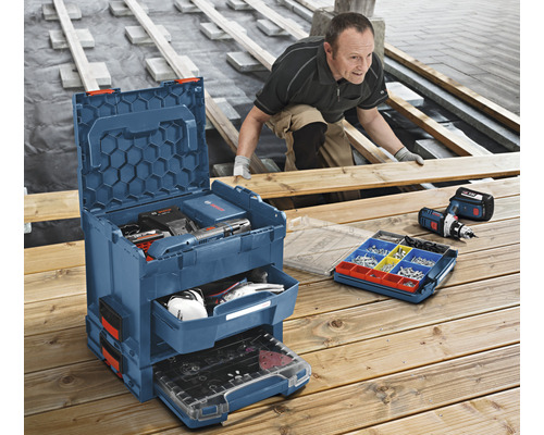 Scène de chantier avec artisan, boîte à outils avec outils et visseuse sans fil sur une terrasse en bois.