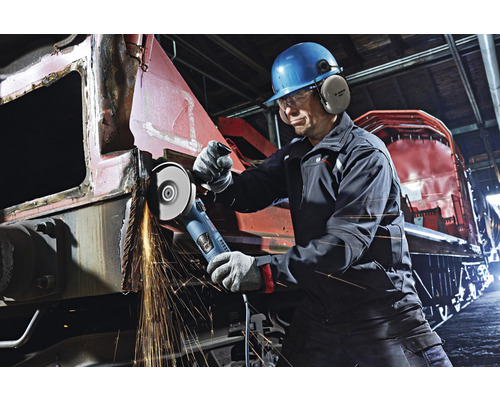 Un homme portant un casque et des protections auditives travaille le métal avec une meuleuse d''angle, des étincelles jaillissent.