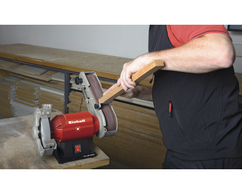 Ein Mann schleift ein Holzstück mit einer Einhell Tischschleifmaschine