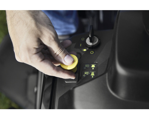 Main actionnant un bouton sur un tracteur de jardin