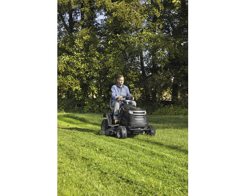 Mann fährt Rasentraktor auf Rasenfläche.