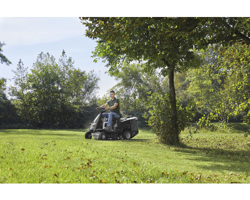 Ein Mann fährt mit einem Rasentraktor über eine Wiese.