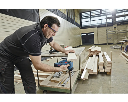Un homme utilise une scie sauteuse pour couper un morceau de bois.