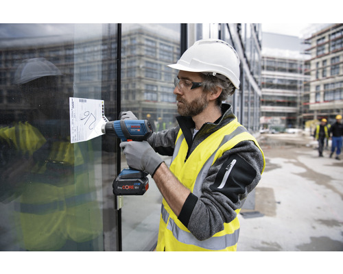 Ein Bauarbeiter verwendet eine Heißluftpistole, um ein Etikett von einer Glasscheibe zu entfernen.