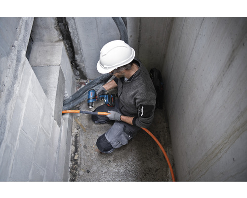 Handwerker bohrt mit Akku-Bohrhammer in Betonwand