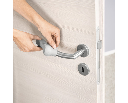 Une personne fixe une extension de poignée sur une poignée de porte en acier inoxydable