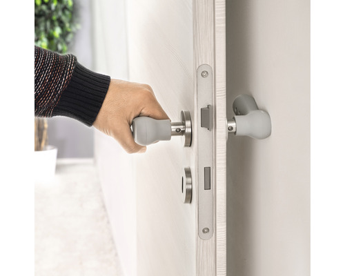 Une personne ouvre une porte avec une poignée de porte avec extension de poignée.