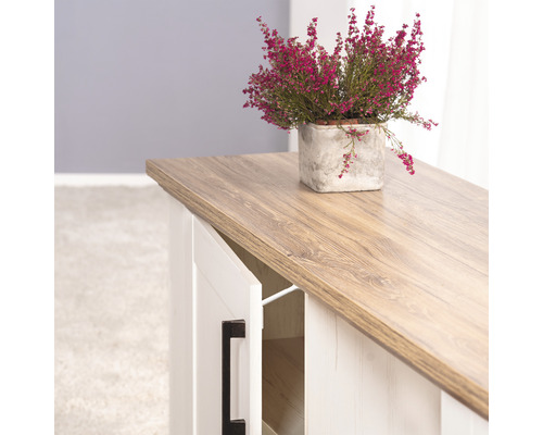 Anrichte mit Holzmuster und offener Tür, darauf eine Heidekraut Pflanze in einem Topf