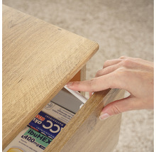 Holzkommode mit einer Hand, die eine Schublade mit Medikamenten öffnet.