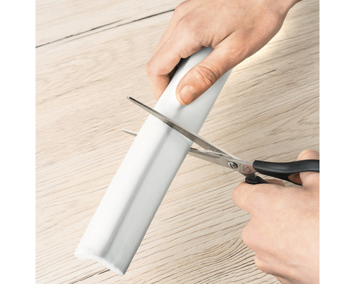 Eine Person schneidet einen Eckenschutz mit einer Schere.