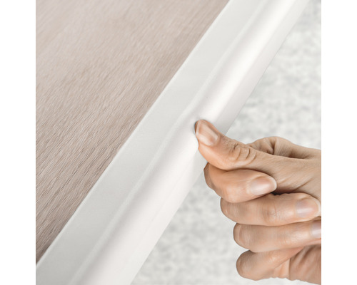 Hand befestigt Sockelleiste an der Wand