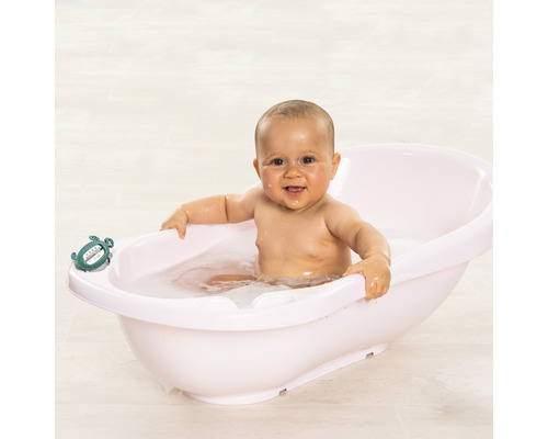 Un bébé est assis dans une baignoire pour bébé avec un thermomètre de bain tortue.