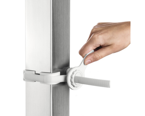 Main actionnant le tendeur sur un poteau en acier inoxydable