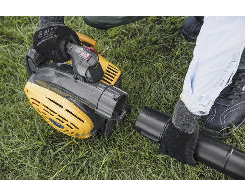 Ein gelber Laubsauger wird auf einer Rasenfläche montiert.